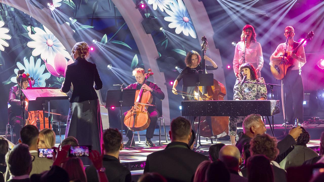 © ORF/Landesstudio Steiermark/Regine Schoettl Ina Regen am Klavier und das Kammerorchester Lipizzanerheimat bei ihrem Auftritt auf der Bühne vor Blumenprojektionen