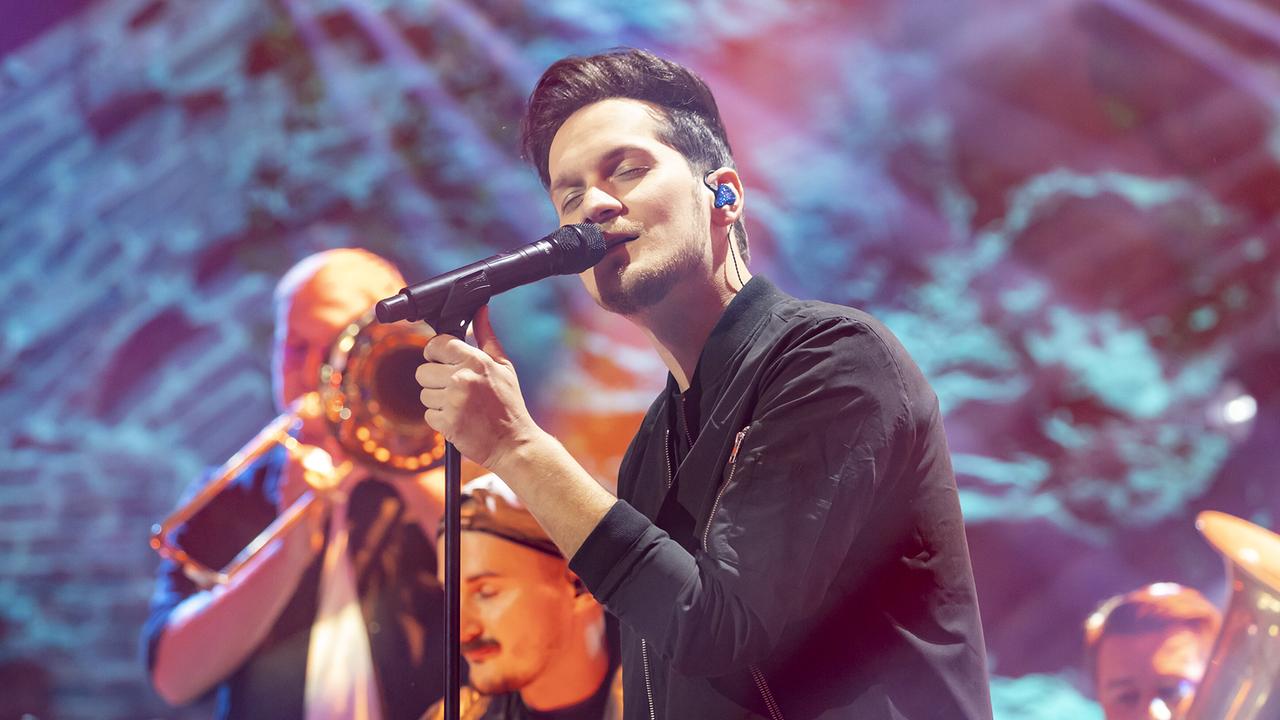 © ORF/Landesstudio Steiermark/Regine Schoettl Der Sänger von Tagtraeumer performt vor der Bläsergruppe "Brass Cuvée" am Mikrofon.