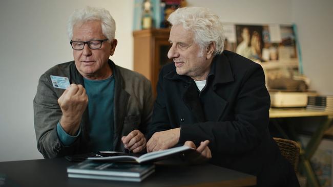 Miroslav Nemec und Udo Wachtveitl sitzen an einem Tisch und betrachten den Dienstausweis.