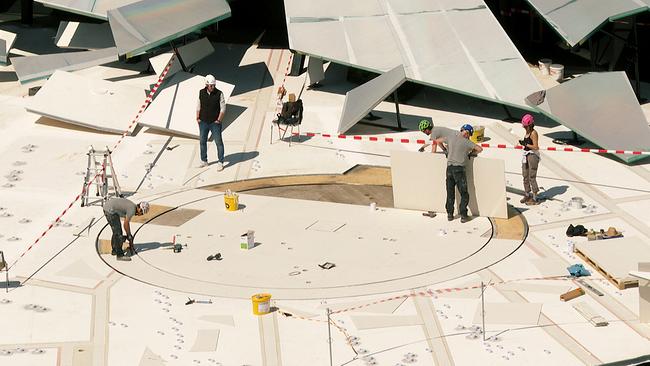 © ORF/Landesstudio Vorarlberg Aufbau des Bühnenbilds für Verdis La traviata auf der Seebühne in Bregenz: Mehrere Bauarbeiterinnen und Bauarbeiter montieren auf einer großen weißen Fläche Teile einer geometrischen Konstruktion.