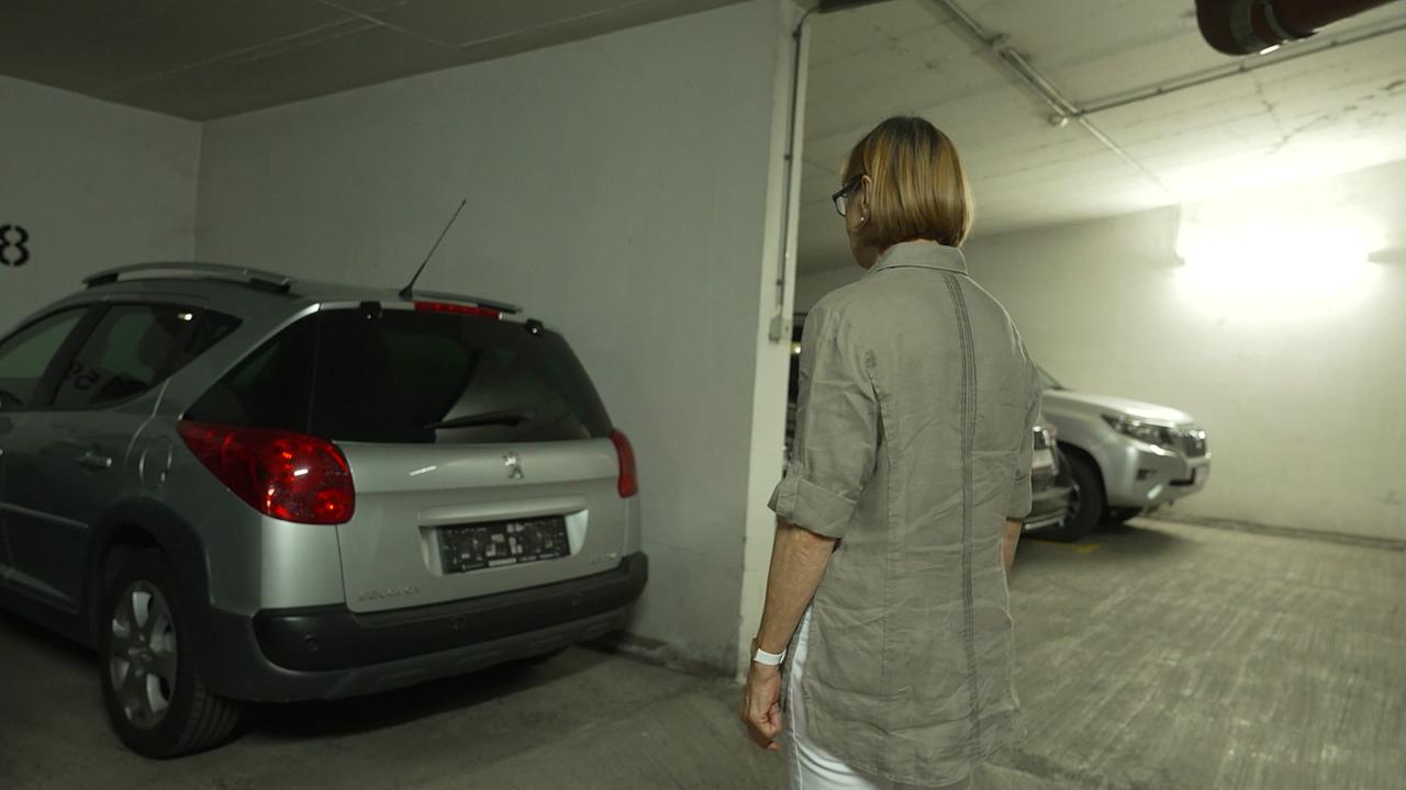 Frau B. steht in einer Garage vor ihrem silbernen Auto. Es fehlt das Kennzeichen.