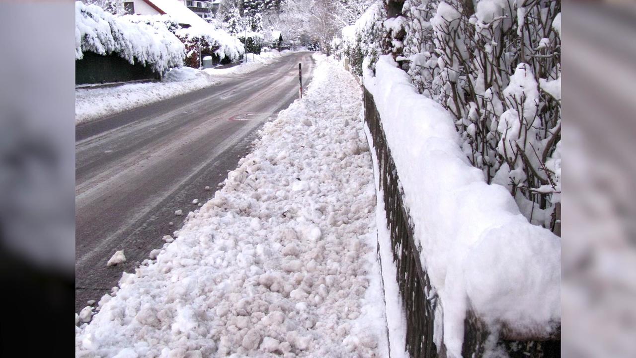 Man sieht den Gehsteig vollgeräumt mit Schnee