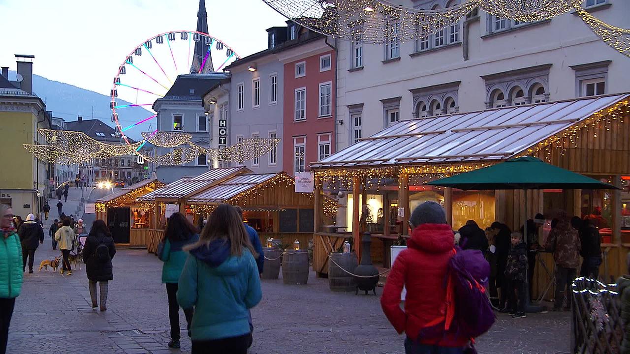 Verkaufshütten und Menschen am  Weihnachtsmarkt in der Fussgängerzone in Villach.