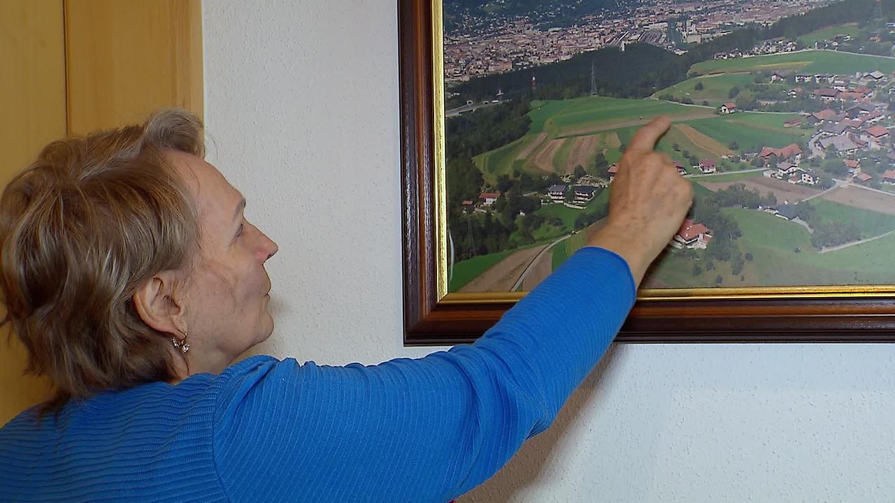 Frau W. zeigt auf einem Foto ihrer Felder, wo ein vermeindlicher Kriegsbunker sein soll.