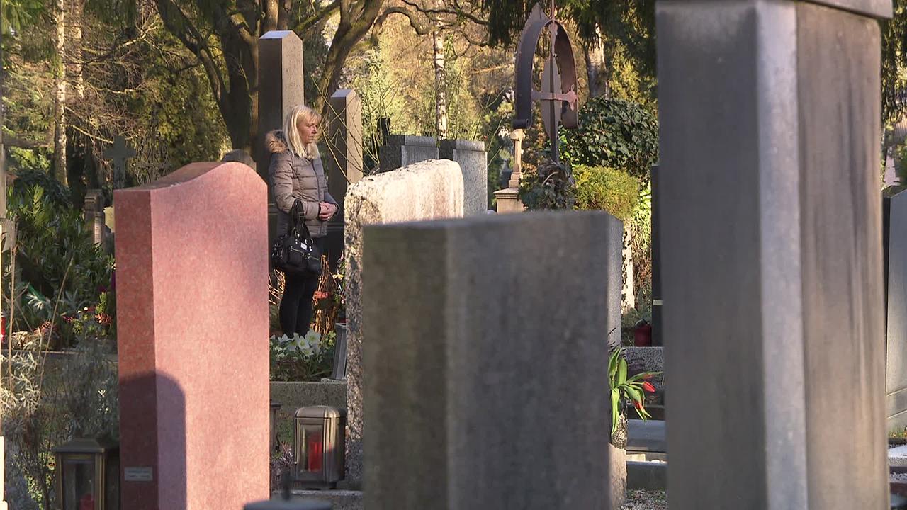 Frau F. steht am Friedhof am Grab ihrer Mutter.
