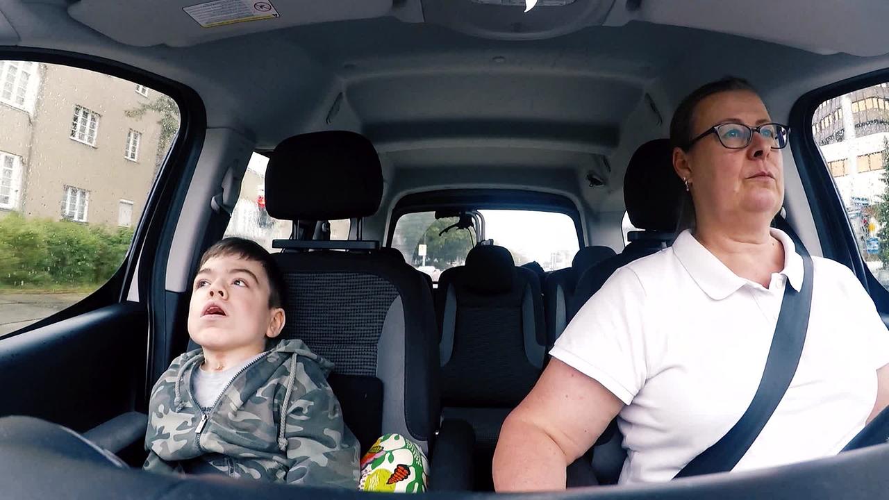 Fritz, ein junger Mann mit Behinderung, sitzt mit seiner Mutter im Auto auf der Fahrt zu seiner Therapie.