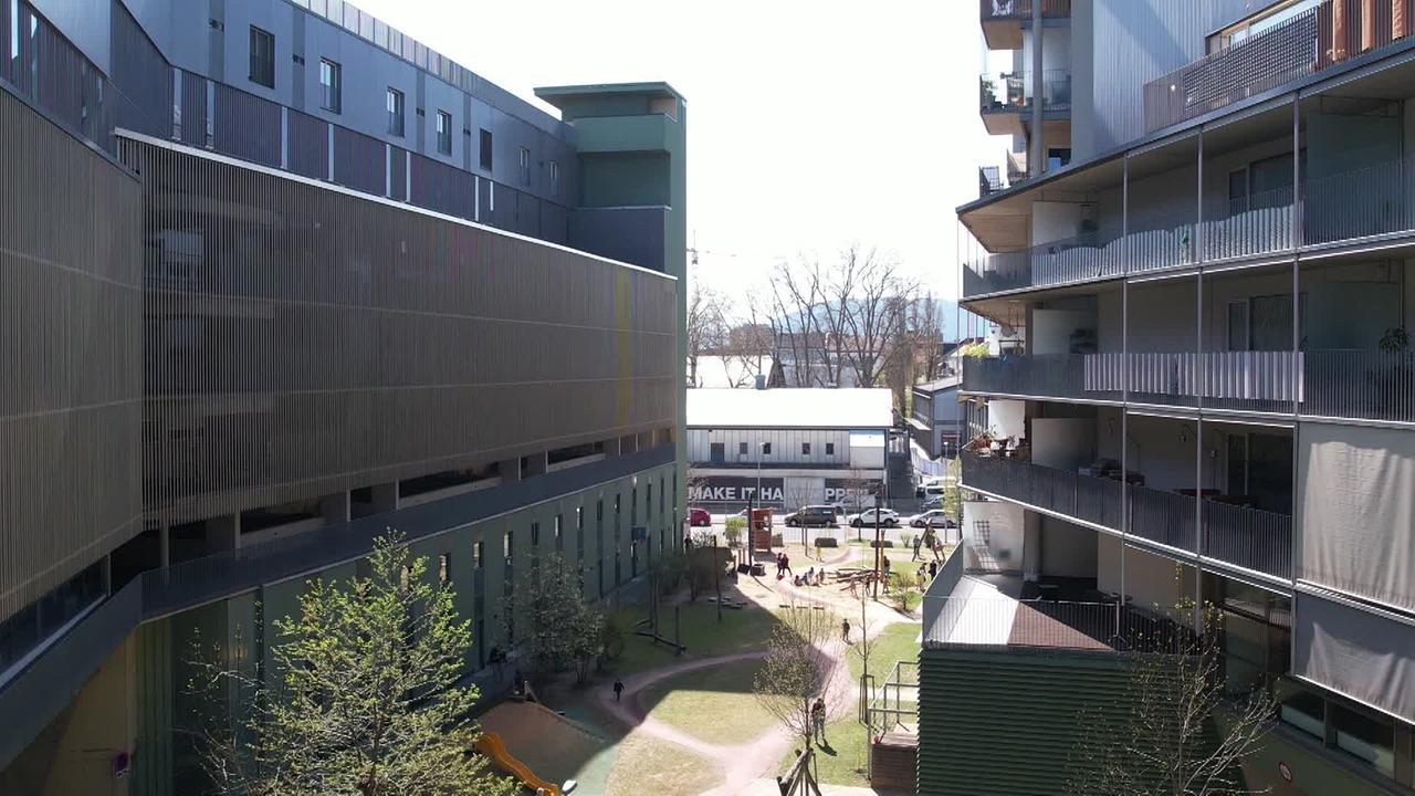 Am Bild sind zwei mehrgeschossige Wohnhäuser zu sehen mit Grünfläche und Spielplatz in der Mitte. Der Beitrag handelt von den Wohnungen in dieser Anlage.