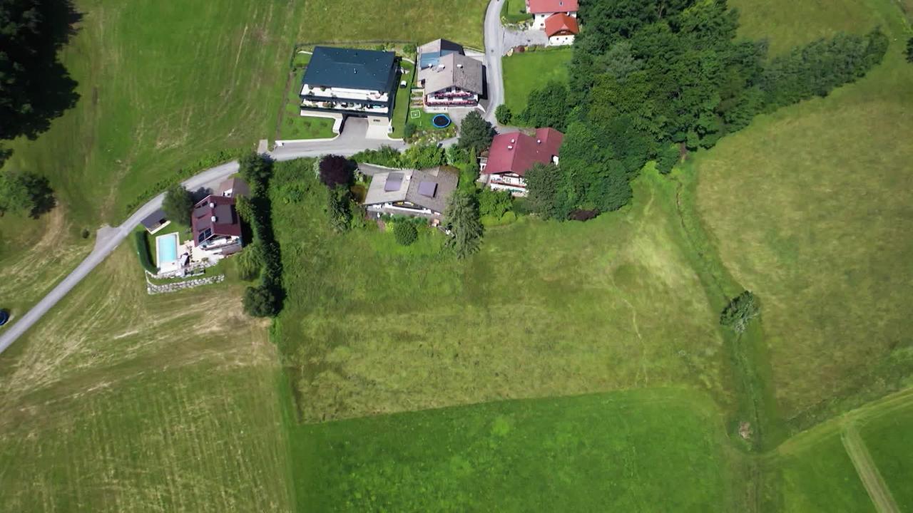 Am Bild sind Häuser aus der Luftperspektive zu sehen inmitten von Grünland. Dort soll gebaut werden und eine Zufahrt ermöglicht werden.