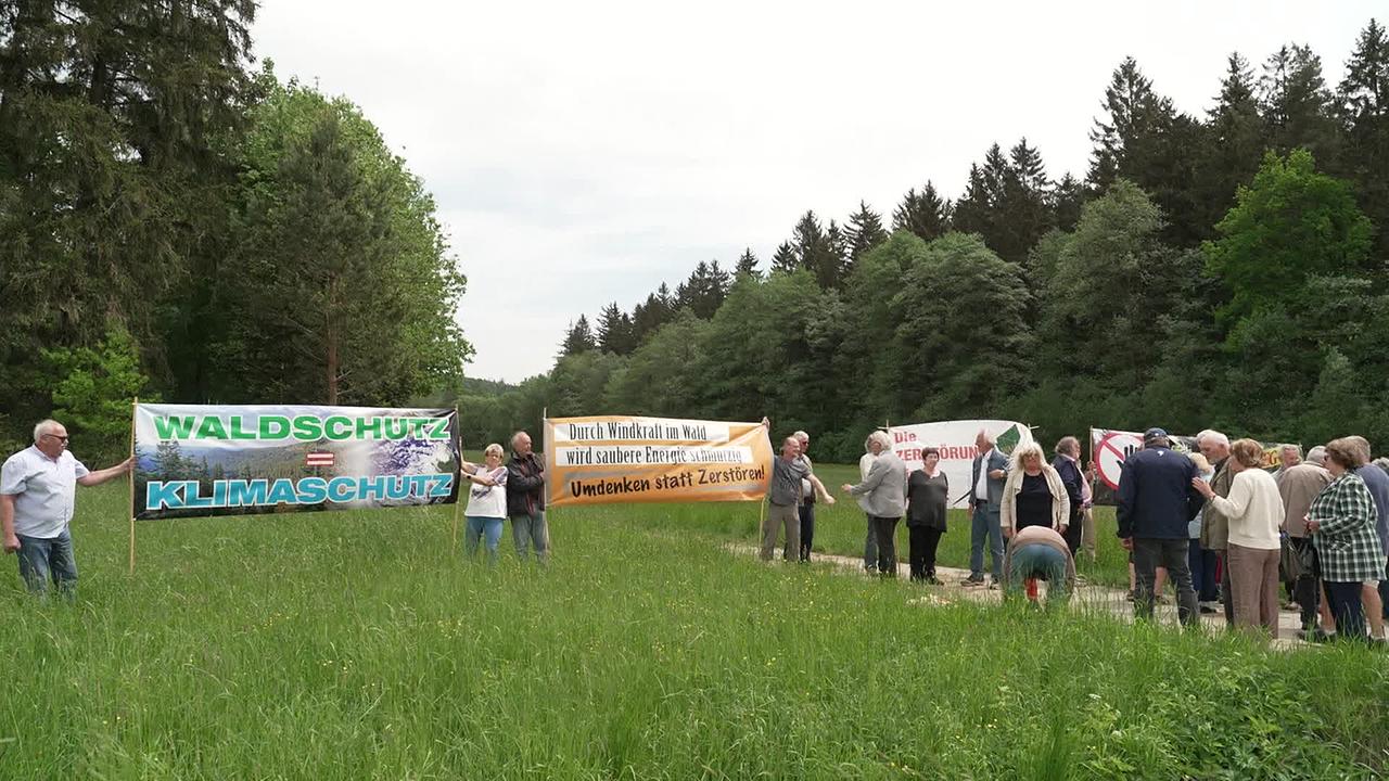 Inmitten von Natur demonstrieren Windkraftgegner/innen mit Plakaten gegen den geplanten Bau von Windrädern im Waldviertel.