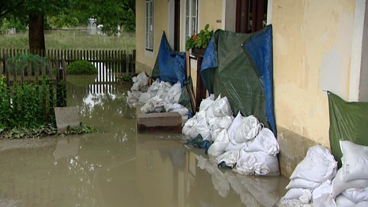 Am Bild ist ein Wohnhaus im Hochwasser zu sehen. Sandsäcke sollen vor dem Eindringen des Wassers schützen. 