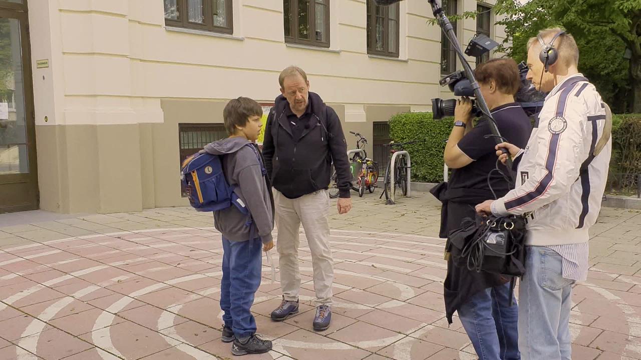 Alexander, ein elfjähriger Bub mit Autismus wird vom Vater von der Schule abgeholt. Sie stehen vor einem Kamerateam. 