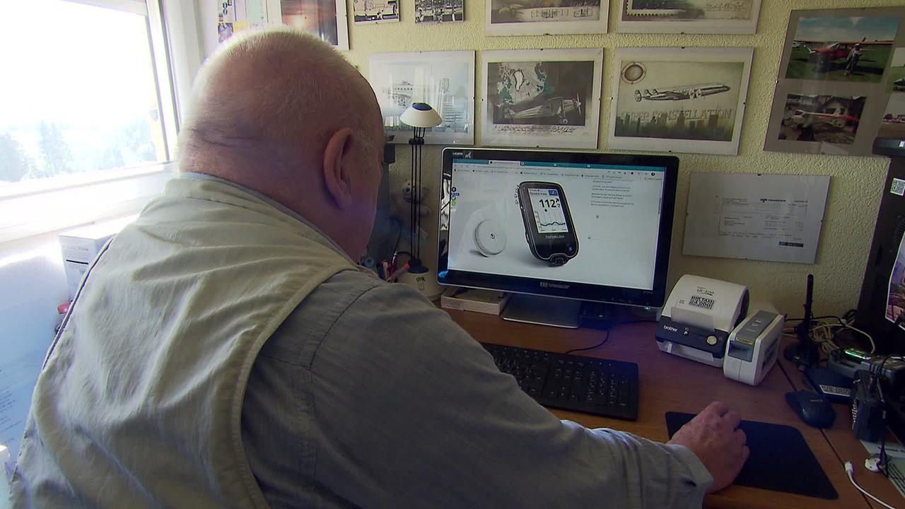 am Bild ist Herr G. der an seinem Schreibtisch sitzt. Am Bildschirm seines Computers ist ein Diabetikermessgerät zu sehen. Ein solches Messgerät würde er brauchen, damit er sich nicht täglich mehrmals in die Finger stechen muss.