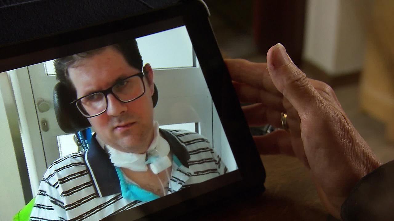 Die Mutter von Robert H. zeigt auf einem Tablet private Aufnahmen von ihrem Sohn, die im Unfallkrankenhaus gemacht wurden. Er sitzt im Rollstuhl und hat einen künstlichen Ausgang am Hals.