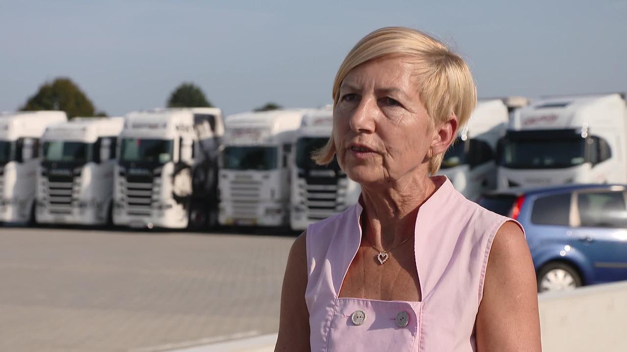 © ORF / Klaus Ibitz Am Bild steht Frau H. vor einem Parkplatz auf dem ein LKW neben dem anderen geparkt ist.