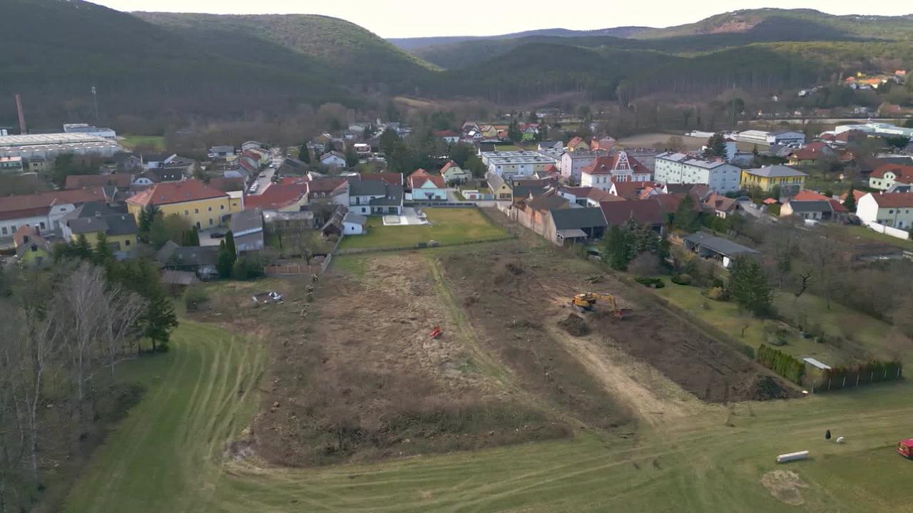 Am Bild ist eine Luftaufnahme von einer Wiese in Berndorf. Die Wiese wird gerade von einem Bagger umgegraben. Eine große Fläche ist bereits umgegraben und gerodet. Im Hintergrund sieht man die Ortschaft von Berndorf.