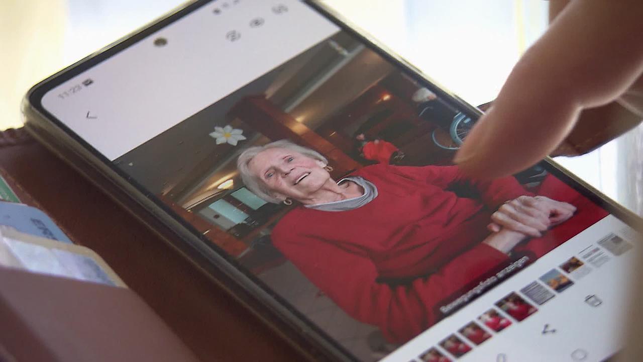 © ORF + Privatfoto Am Bild ist ein Handy zu sehen auf dem ein Foto der pflegebedürftigen Mutter von Hrn. L. aufgerufen wurde. Sie sitzt in einem roten Pullover in einem Rollstuhl und lächelt ihren Sohn an.
