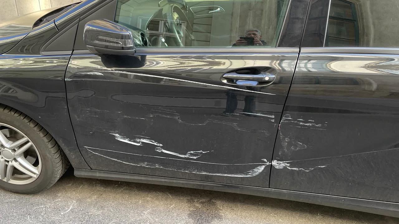 © Privataufnahme Am Bild ist ein schwarzes Auto. Die Fahrerseite hat weiße Kratzer, Abschürfungen und ist teilweise eingedrückt. Es ist das Foto vom Parkschaden des Herrn S.
