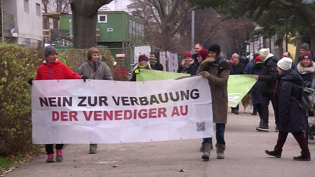 Am Bild sind eine Gruppe von Leuten, die gegen die Verbauung der Venediger Au in Wien protestieren. Sie tragen Transparente auf denen steht: "Nein zur Verbauung der Venediger Au"