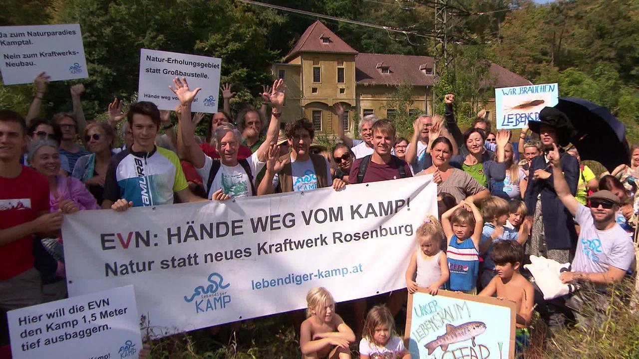 © ORF Am Bild sind Menschen, die gegen ein neues Kraftwerk am Kamp demonstrieren. sie halten Transparente und Schilder hoch mit Aufschriften wie: EVN Hände weg vom Kamp. Natur statt neues Kraftwerk Rosenburg. Oder Hier will die EVN den Kamp 1,5 Meter tief ausbaggern.