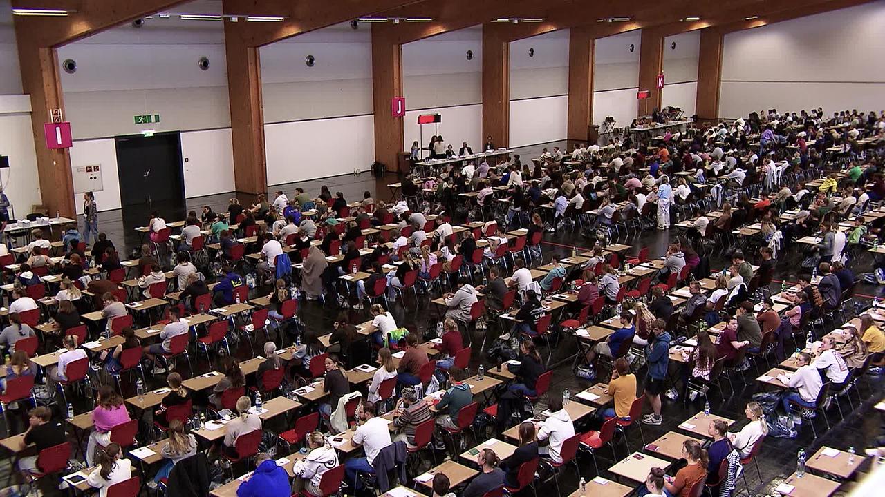 © ORF / Matthias Witzemann Am Bild ist ein großer Saal zu sehen, in dem viele junge Menschen an Tischen sitzen und Prüfungen schreiben, wie die Aufnahmeprüfung für Medizin.