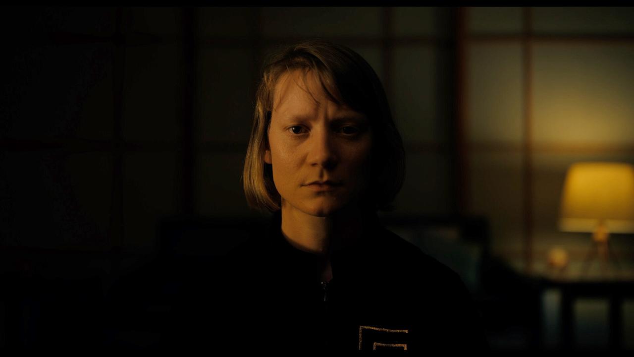 MS Novak steht in einem dunklen Raum nur teilweise beleuchtet und blickt nach vorne.