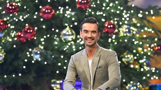 © ORF/MDR/JürgensTV/Dominik Beckmann Florian Silbereisen auf einer Coach im Studio vor einem festlich dekorierten Christbaum