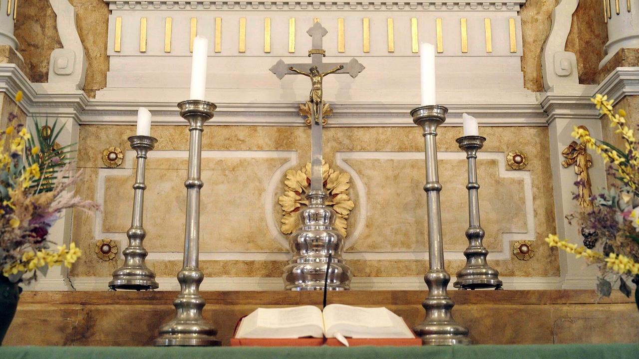 © ORF/Good Media Solutions Der Altar der evangelische Kirche mit Kreuz, Kerzenleuchtern und aufgeschlagener Bibel in Bad Goisern