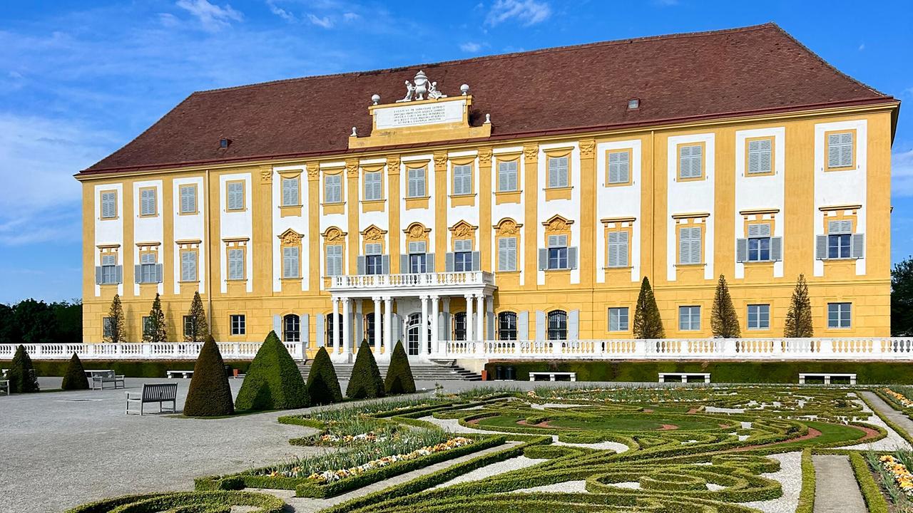© ORF/Ralph Huber-Blechinger Barockgarten von Schloss Hof mit symmetrisch angelegten Buchsbaumhecken, Blumenbeeten und dem Schlossgebäude im Hintergrund.