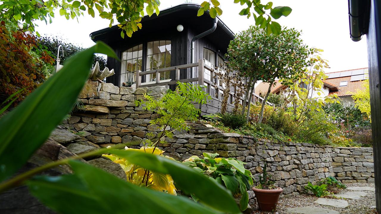 © Leopold Mayrhofer/Natur im Garten/Leopold Mayrhofer, A.Wildgansstr. 3382 LOOSD. Ein Haus auf einer Steinmauer, umgeben von einem asiatisch angehauchten Garten.