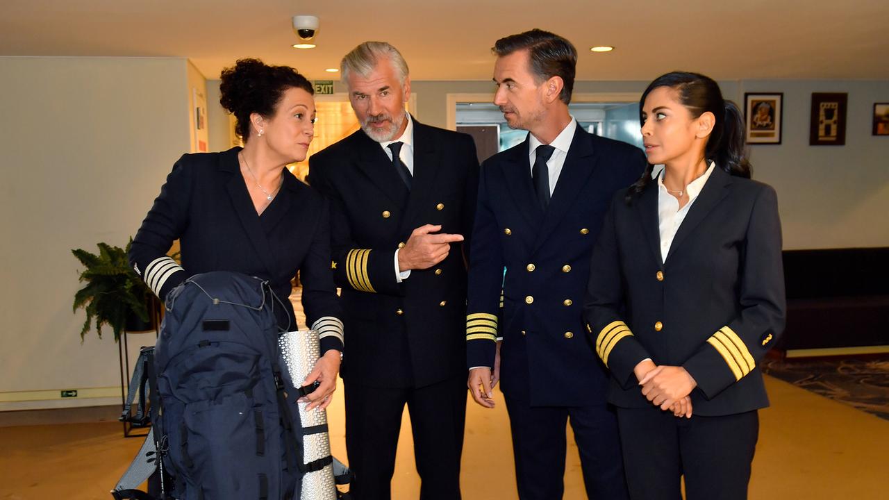 Hanna Liebhold, Staff-Kapitän Martin Grimm, Kapitän Max Parger und Dr. Jessica Delgado in dunklen Uniformen unterhalten sich in einem hellen Innenraum über Islands mythische Wesen.