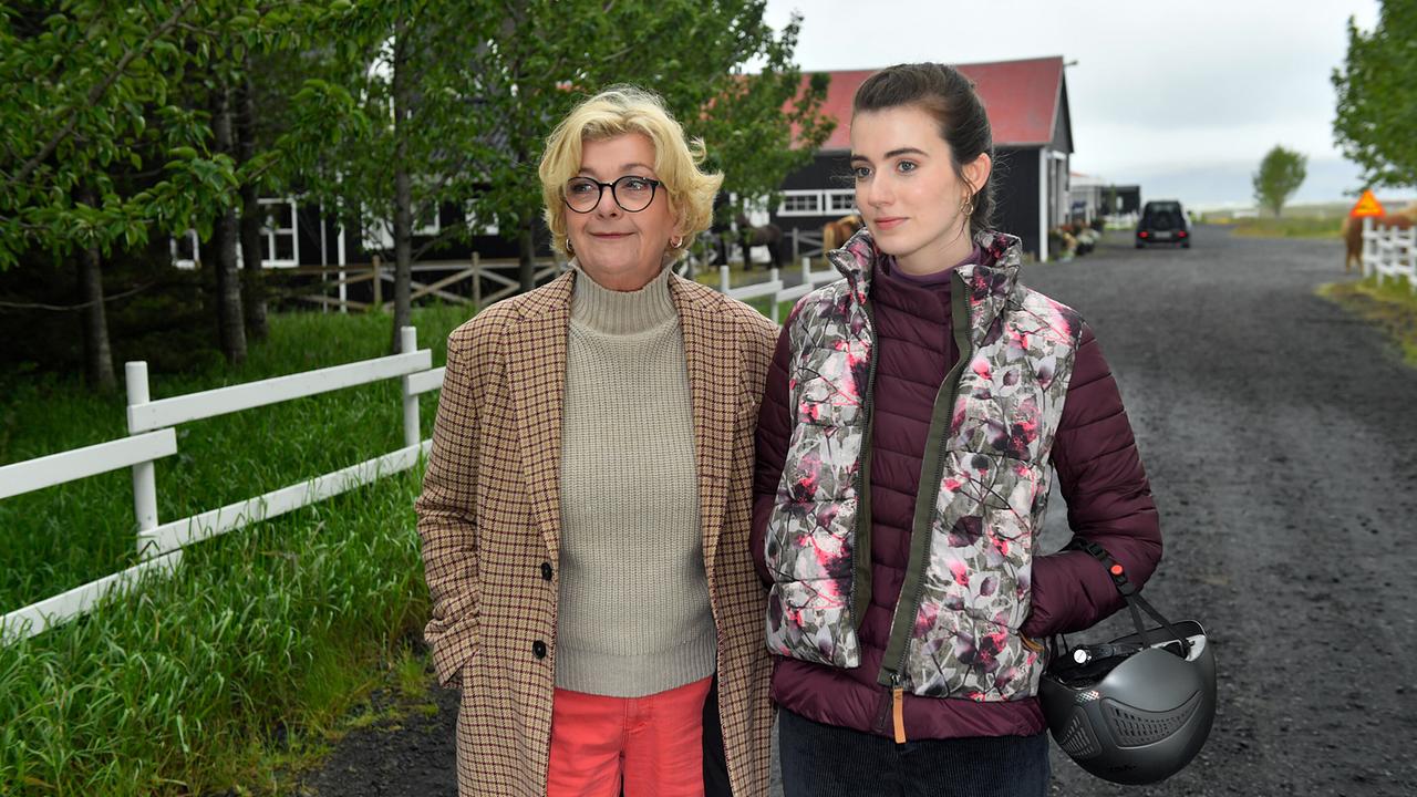Ronja Küpper mit einem Fahrradhelm im Arm und ihre Großmutter Evelyn Küpper stehen auf einem Kiesweg vor ländlichen Gebäuden.