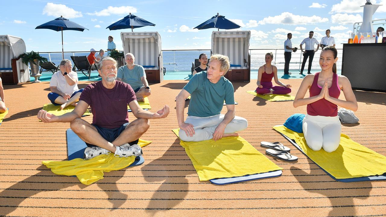 "Das Traumschiff: Argentinien": Unter Anleitung der Lehrerin (Alessandra Meyer-Wölden, vorne r.) versuchen sich Konrad Schneider (Kai Wiesinger, vorne l.) und Andreas Weingärtner (Kai Lentrodt, vorne mi.) im Yoga.