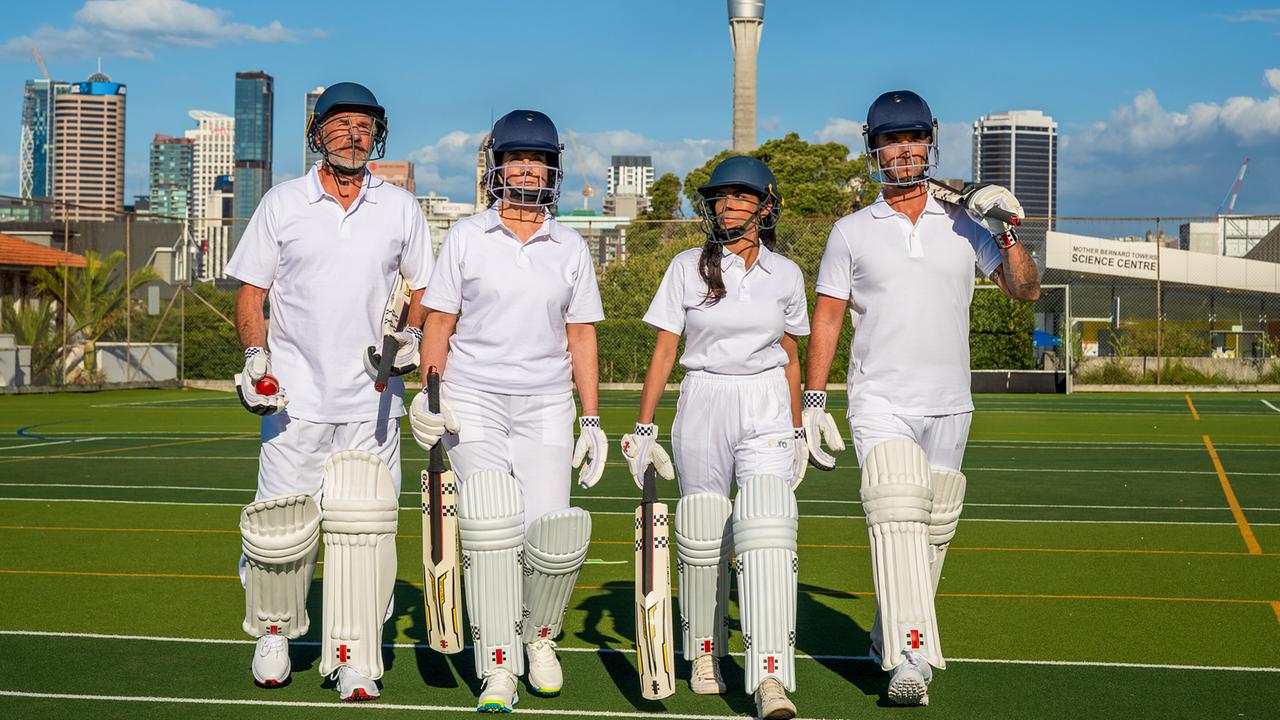 Florian Silbereisen mit drei seiner Crewmitglieder in Cricket-Ausrüstung gehen nebeneinander auf einem Sportplatz, im Hintergrund ist eine Skyline zu sehen.