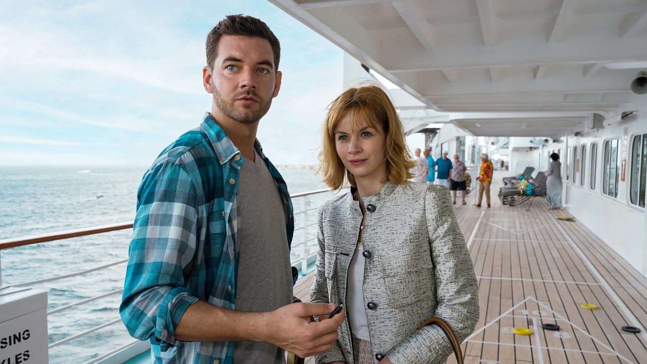 Basti Kugler und Toni Wittig stehen auf dem Außendeck eines Kreuzfahrtschiffs vor dem Meer.