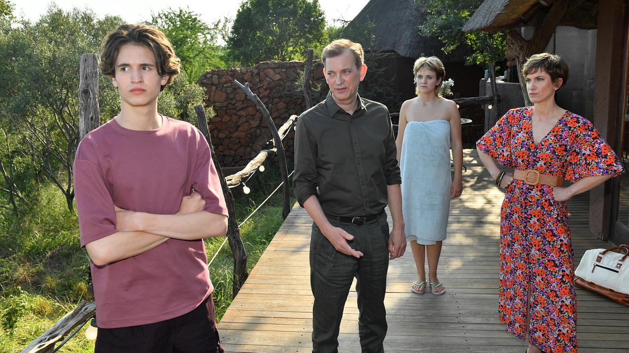 Paul Wagner, Lisa Sommer, Björn Wagner und Katja Sommer stehen auf einem Holzsteg zwischen Lodges inmitten grüner Natur.