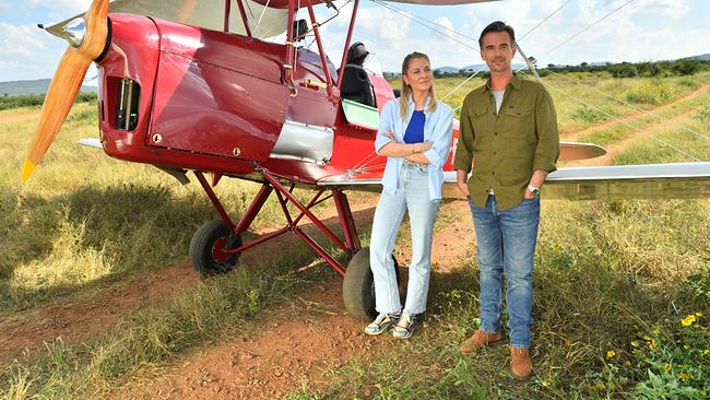 © ORF/ZDF/Dirk Bartling Sophia Berg und Max Parger stehen neben einem roten Doppeldeckerflugzeug auf einer sonnigen Wiese.