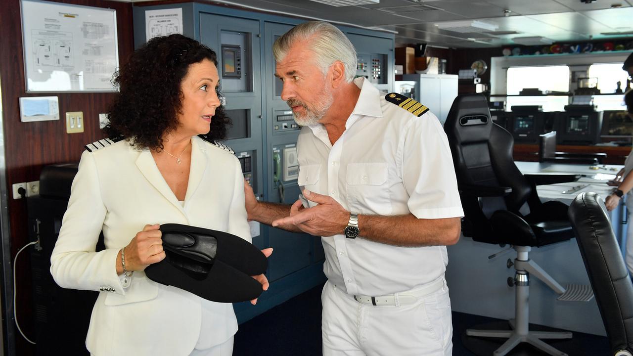 Hanna Liebhold und Staff-Kapitän Martin Grimm in Uniform sprechen miteinander auf der Brücke eines Schiffs.