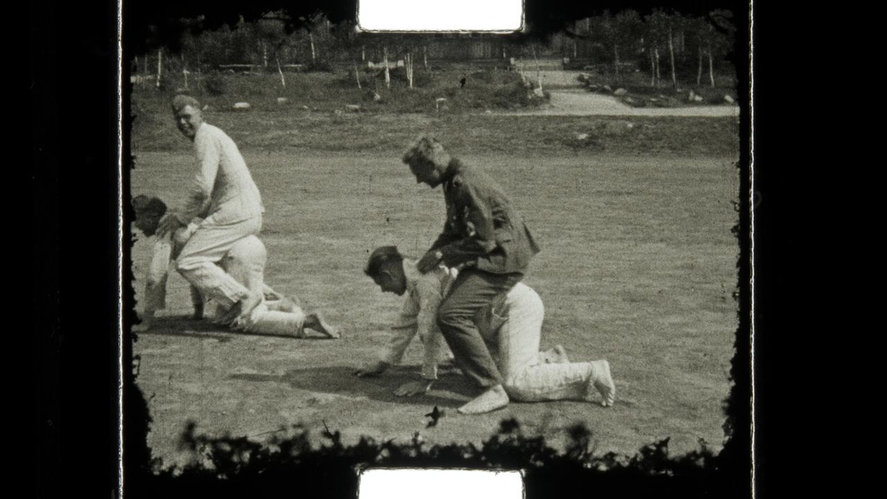 Männer auf Boden kauernd tragen andere Männer auf dem Rücken