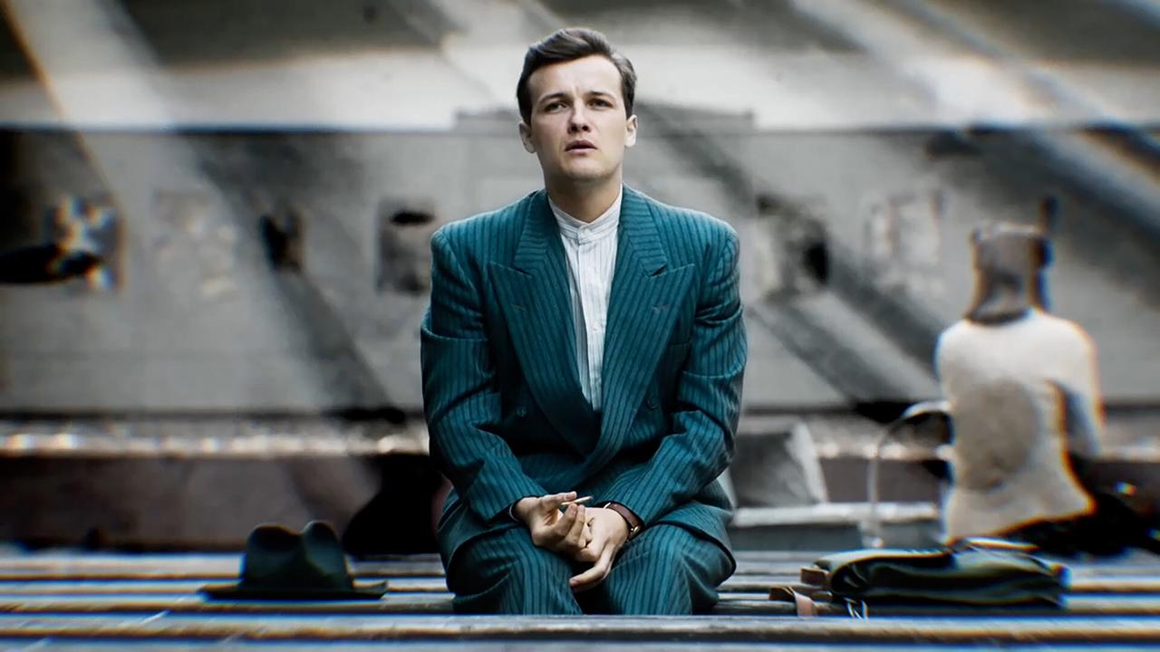 Mann in Nadelstreifanzug siitzt in Halle und sieht nach oben