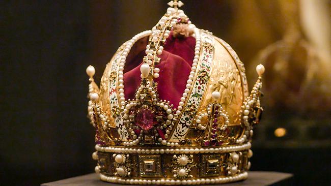 Die prunkvolle Kaiserkrone mit goldenen Reliefs, Perlenreihen und roten Schmucksteinen auf einem dunklen Hintergrund in der Kaiserlichen Schatzkammer in der Wiener Hofburg