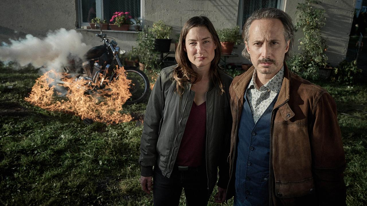 © ORF/BR/ARD Degeto/Hager Moss Film/Bernd Schuller Frederike Bader und Ferdinand Zankl stehen abwartend vor einem brennenden Motorrad.