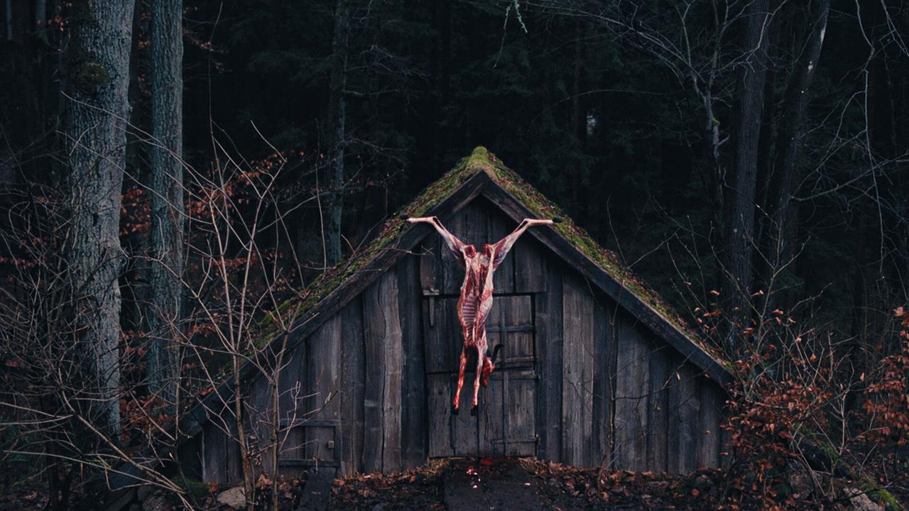 © ORF/Ulrich Seidl Film An einer hölzernen Hütte im Wald hängt ein geschlachteter Tierkörper.