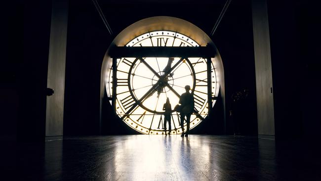 Zwei Menschen stehen vor einer übergroßen Uhr 