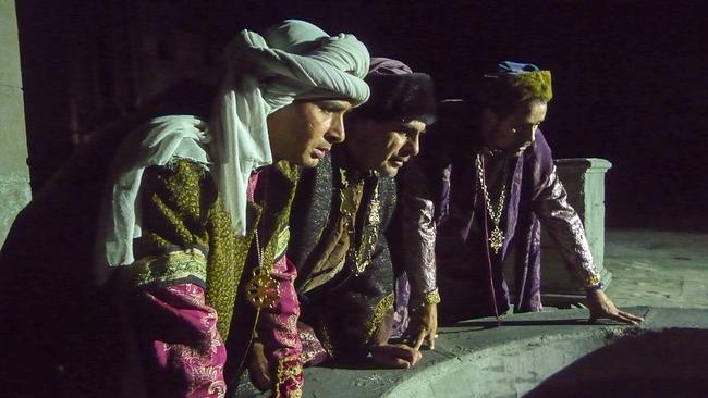 Die Heiligen Drei Könige in historischen Gewändern beugen sich nachts gemeinsam über einen steinernen Brunnen oder eine runde Öffnung und blicken hinein.