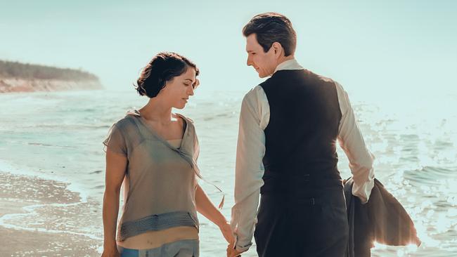 Dora und Franz Kafka gehen Hand in Hand durch das seichte Wasser am Strand.