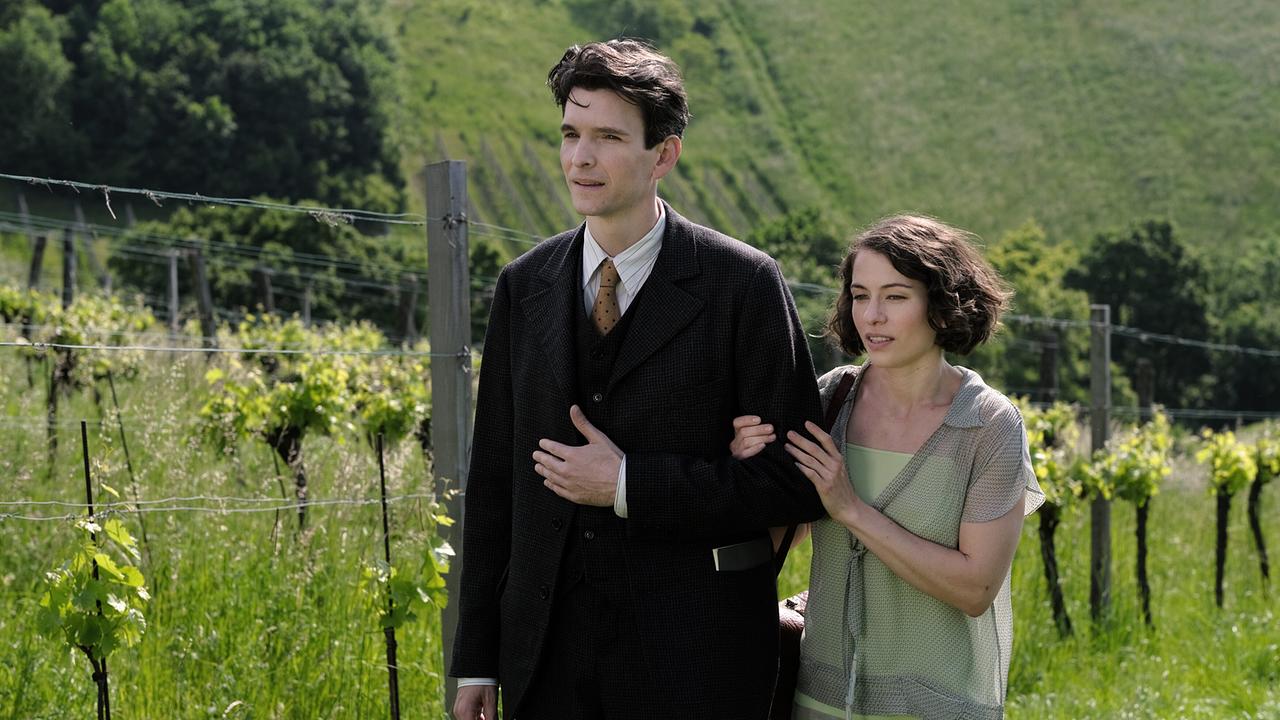 Franz Kafka und Dora spazieren Arm in Arm durch eine grüne Weinlandschaft.