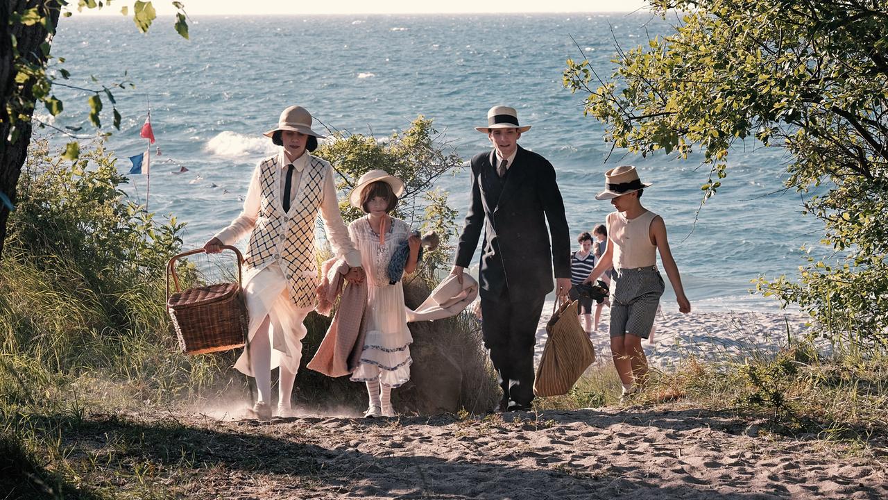 Dora, Gerti, Franz Kafka und Felix geht mit Körben auf einem sandigen Weg vom Meer hinauf.