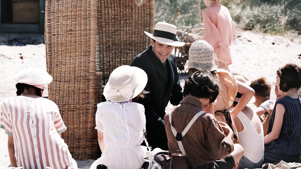 Eine Gruppe von Kindern sitzt am Strand um Franz Kafka bei einem Strandpicknick.