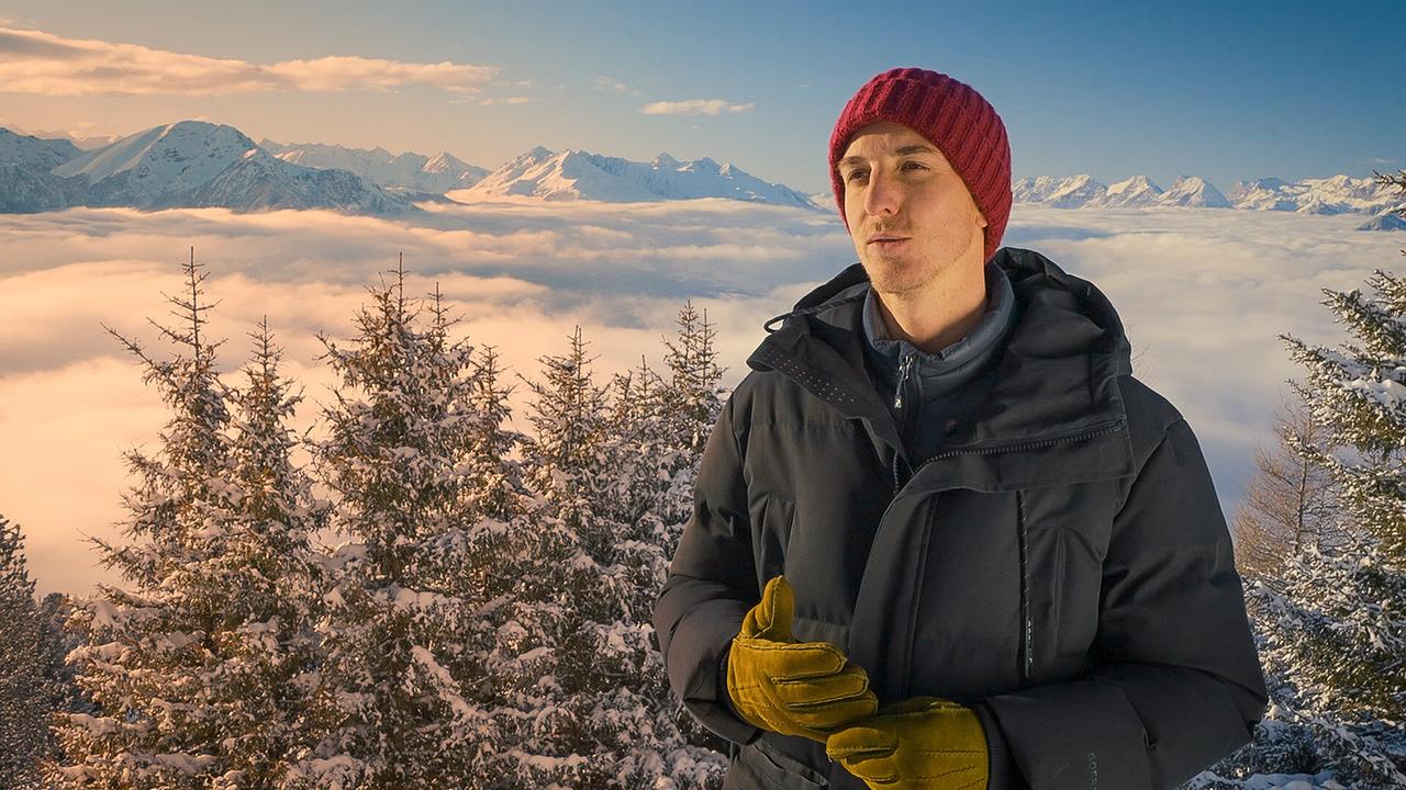 Gregor Schlierenzauer steht auf der Berg Isel-Sprungschanze in winterlicher Berglandschaft über einem Meer aus Wolken beim Interview.