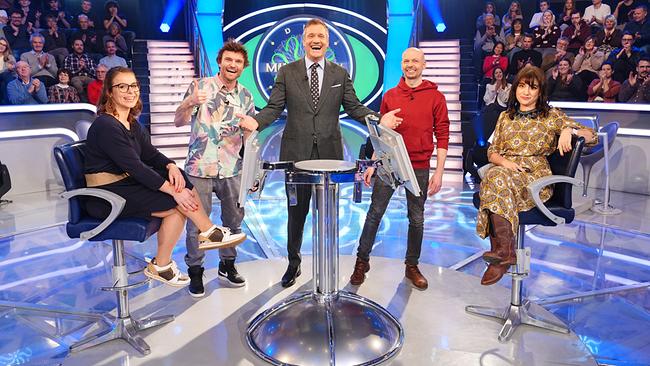 Im hell beleuchteten "Millionenshow"-Studio stehen und sitzen Sandra Schönfelder, Uwe Weitzer, Dominik Aichhorn und Bernadette Schmatzer mit Armin Assinger in der Mitte um den Quiz-Pult, während ein applaudierendes Publikum im Hintergrund zu sehen ist.